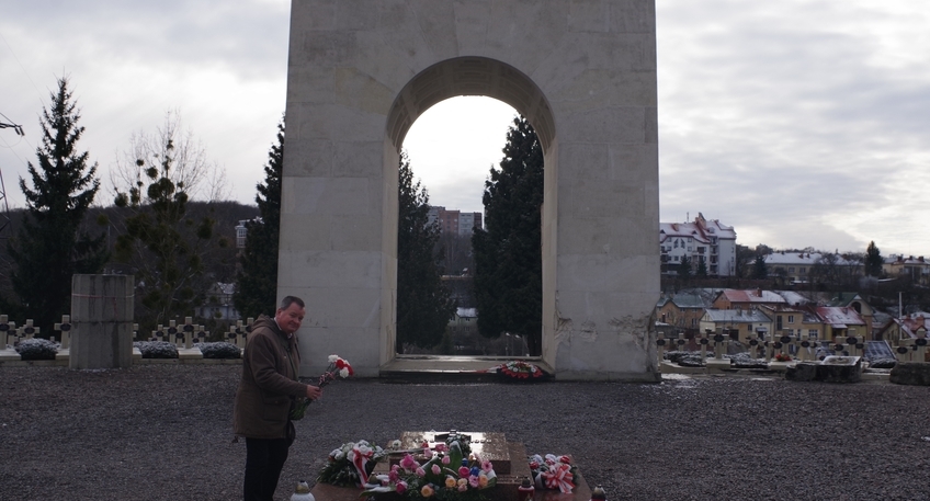 Zdjęcie przedstawia członka zarządu Powiatu Pana Macieja Trąbczyńskiego składającego bukiet biało-czerwonych kwiatów na cmentarzu.