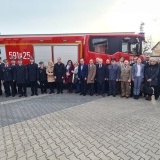 Goście wraz z nowym ciężkim samochodem ratowniczo-gaśniczym przed Komendą Powiatową Państwowej Straży Pożarnej w Szamotułach.