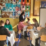 Uczniowie siedzący przy stolikach w 