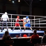 Gala boksu, sędzia i 2 sportowców w niebieskim i czerwonym stroju na ringu