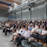 Wielu uczniów Liceum Ogólnokształcącego nr 1 w Szamotułach siedzący na krzesłach i trybunach na powiatowej hali sportowej Szamotulanka 