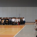 Uczniowie Liceum Ogólnokształcącego nr 1 w Szamotułach siedzący na krzesłach na powiatowej hali sportowej Szamotulanka 