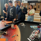 Uczniowie pracującymi nad modelami przy dużym stole ze wzorem planety